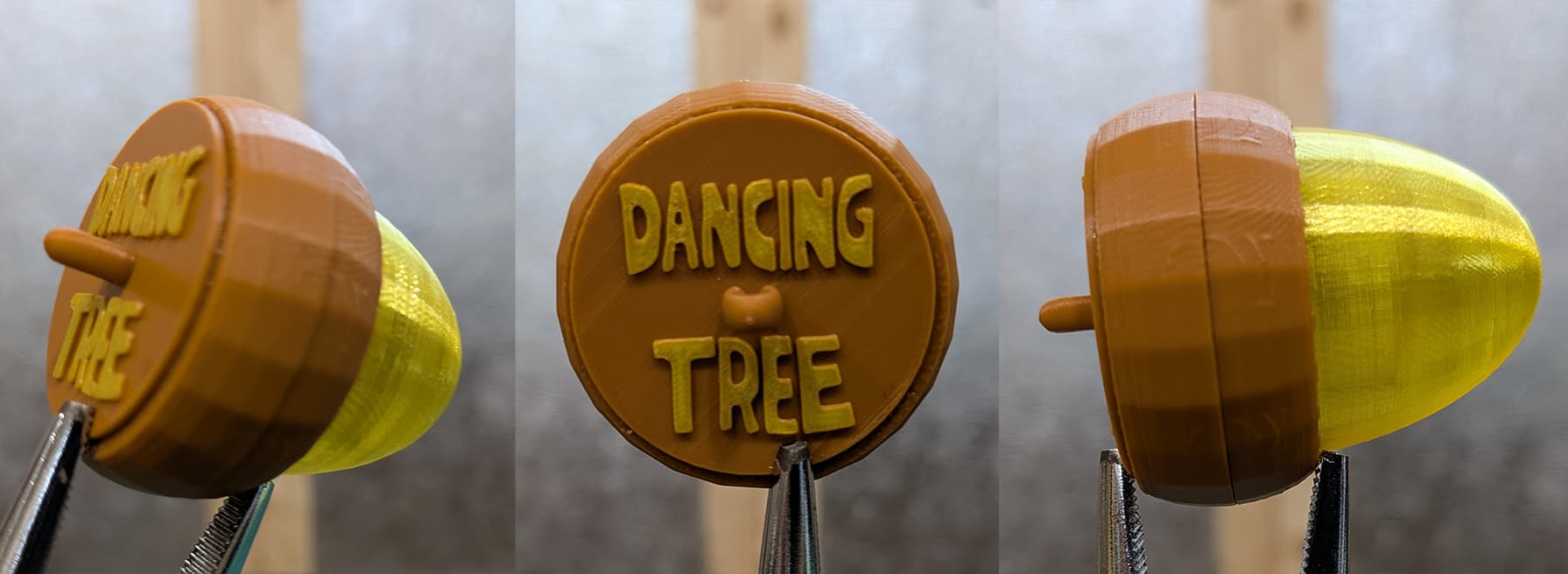 Three views of a 3D-printed acorn keychain. The acorn cap is brown with the words 'DANCING TREE' printed on the front, and the acorn nut is translucent yellow. The keychain is held by tweezers in all three views, showing it from the side, front, and another side perspective.